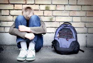 depressed teenage boy sitting on floor with head between knees