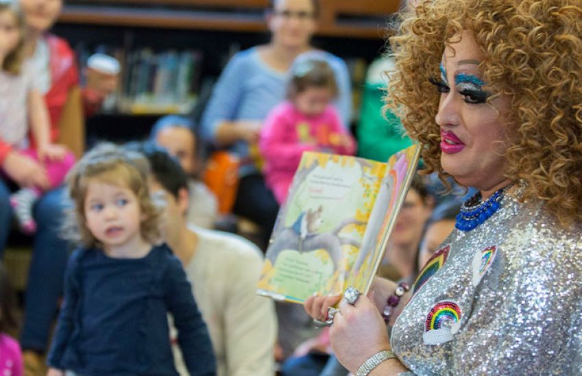 A drag queen reads a book to kids at drag queen story hour