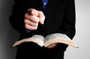 man pointing at camera with Bible in hand