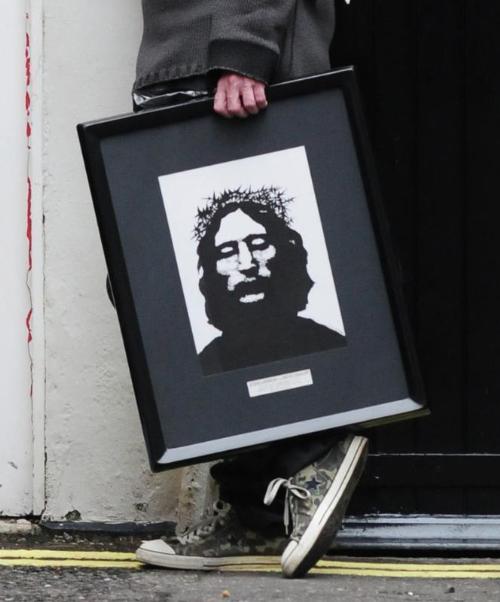 a man holding a black and white painting of Jesus Christ