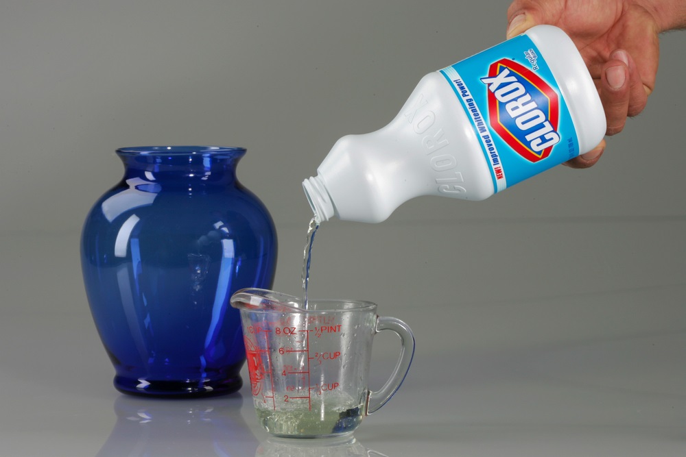 person pouring clorox bleach into measuring cup
