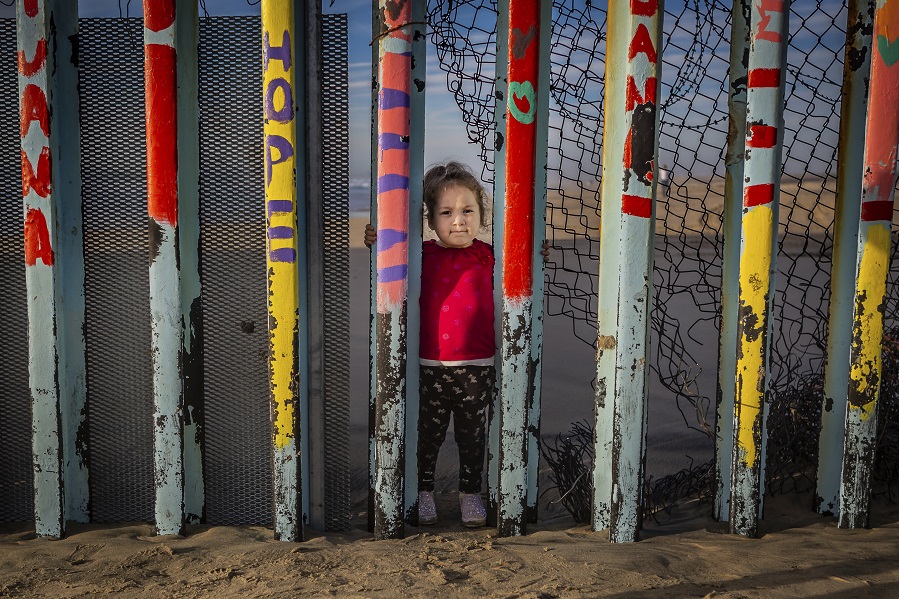 Young girl standing at border fence