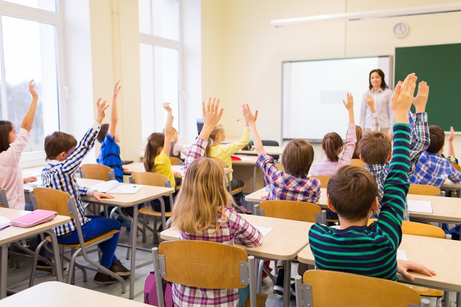 children raising hands in classroom