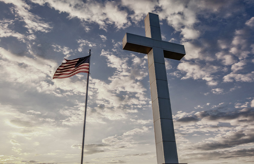 A cross statue and American flag.