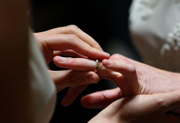 person putting wedding ring on during wedding ceremony