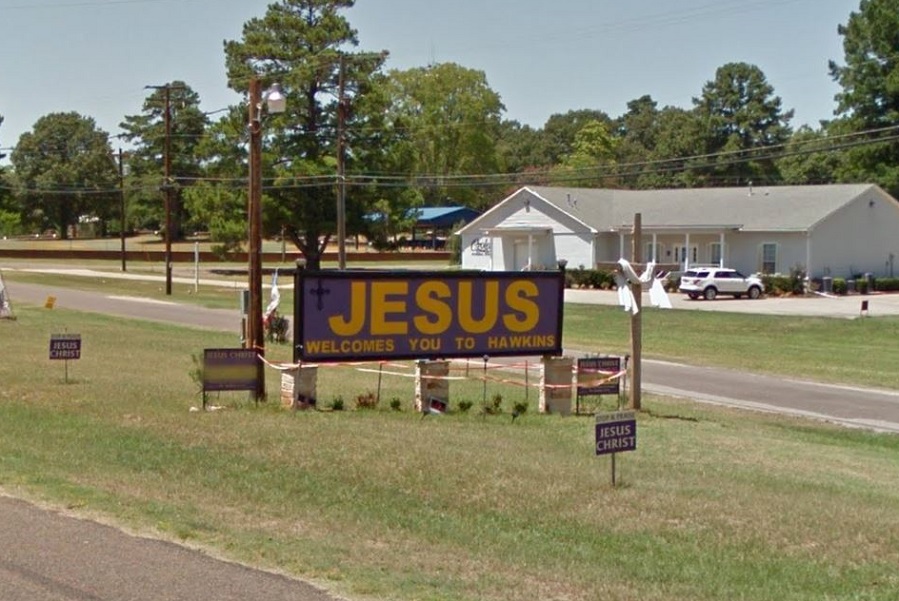 Road sign that says 'Jesus welcomes you to Hawkins'
