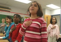 group of children reciting pledge of allegiance in classroom