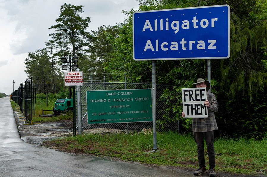 Protester outside Alligator Alcatraz sign