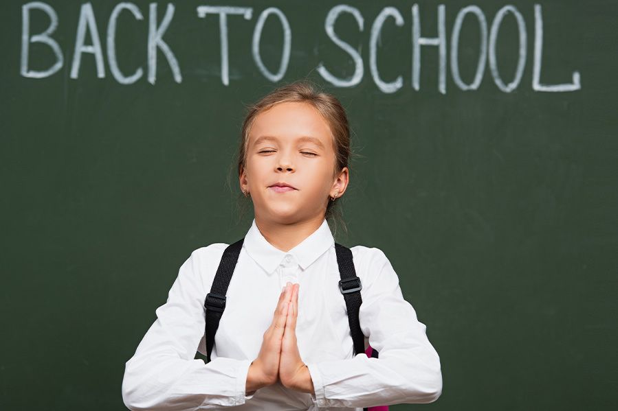 student praying in front of blackboard reading back to school