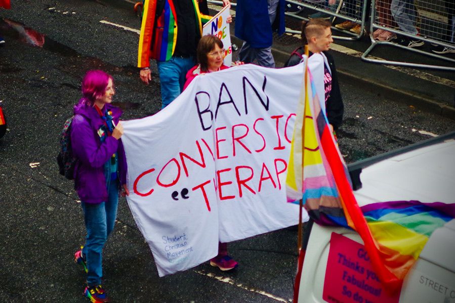 protesters holding sign reading ban conversion therapy