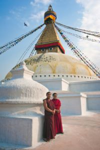 2 monks standing outside Tibetan stupa in the daytime