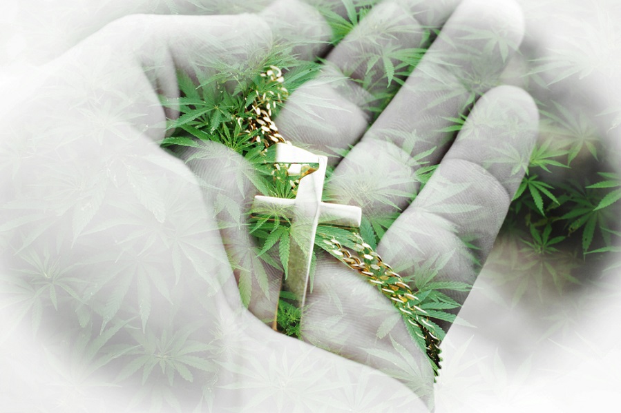 Person holding a cross with cannabis leaves