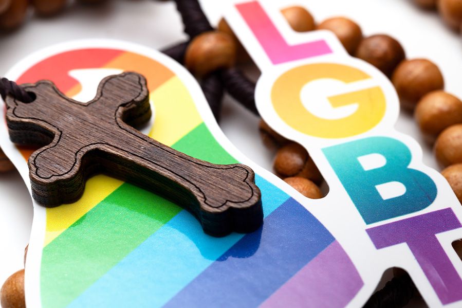 catholic rosary laying on lgbtq rainbow symbol