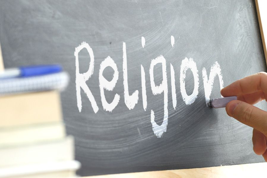 teacher writing religion on school chalk board