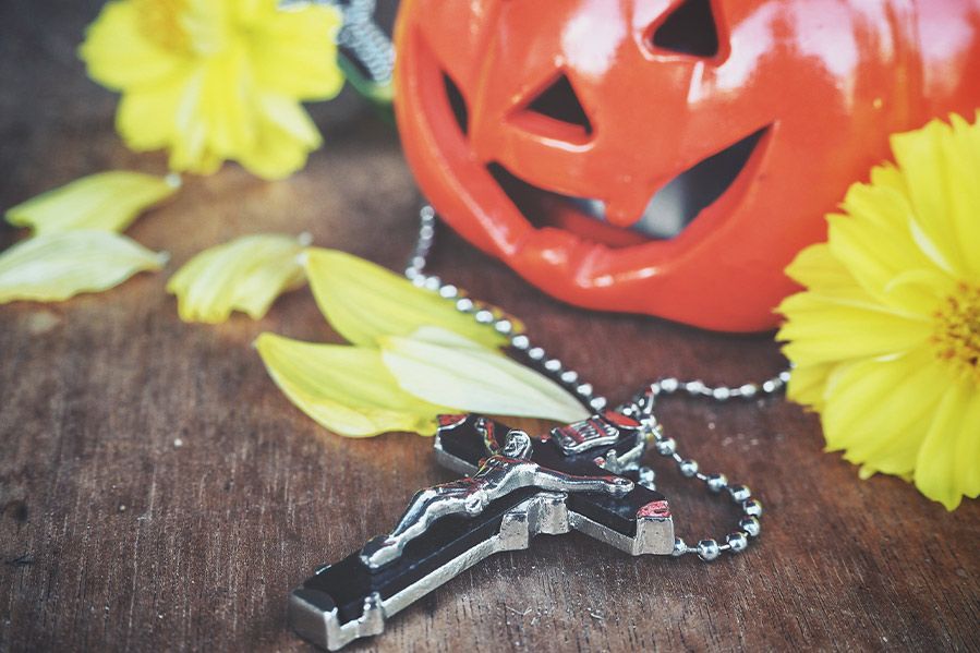a cross on table next to jack o lantern