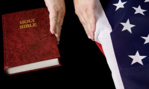 hands separating bible and american flag in depiction of separation of church and state