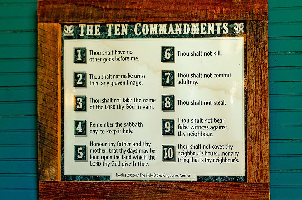 A framed copy of the ten commandments is posted on a green clapboard wall.