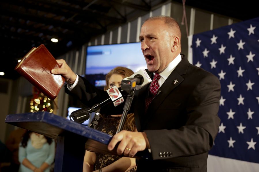 Congressman Clay Higgins addresses a crowd while holding a Bible