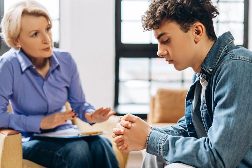 A counselor sits and talks with a teenaged patient.