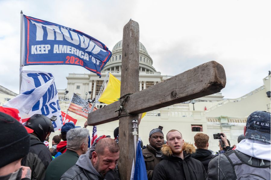A protester carries a wooden cross at the Capitol building