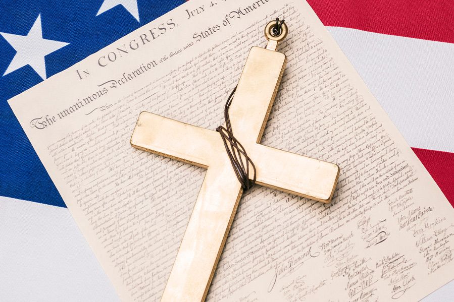 christian cross resting on constitution and american flag