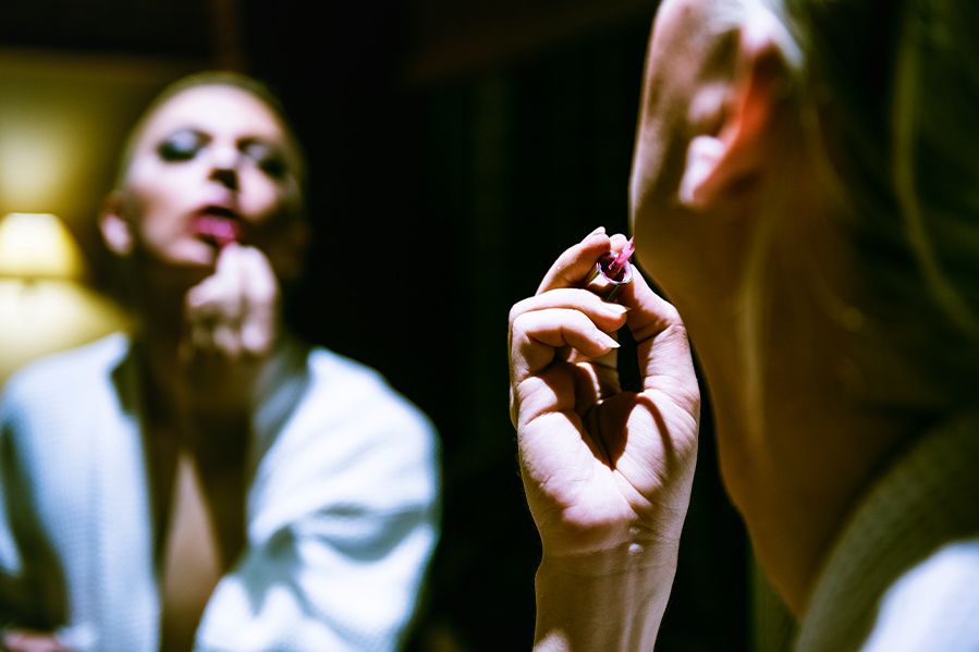 drag queen applying lipstick in mirror