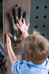 Child comparing hand size to Orangutan bust