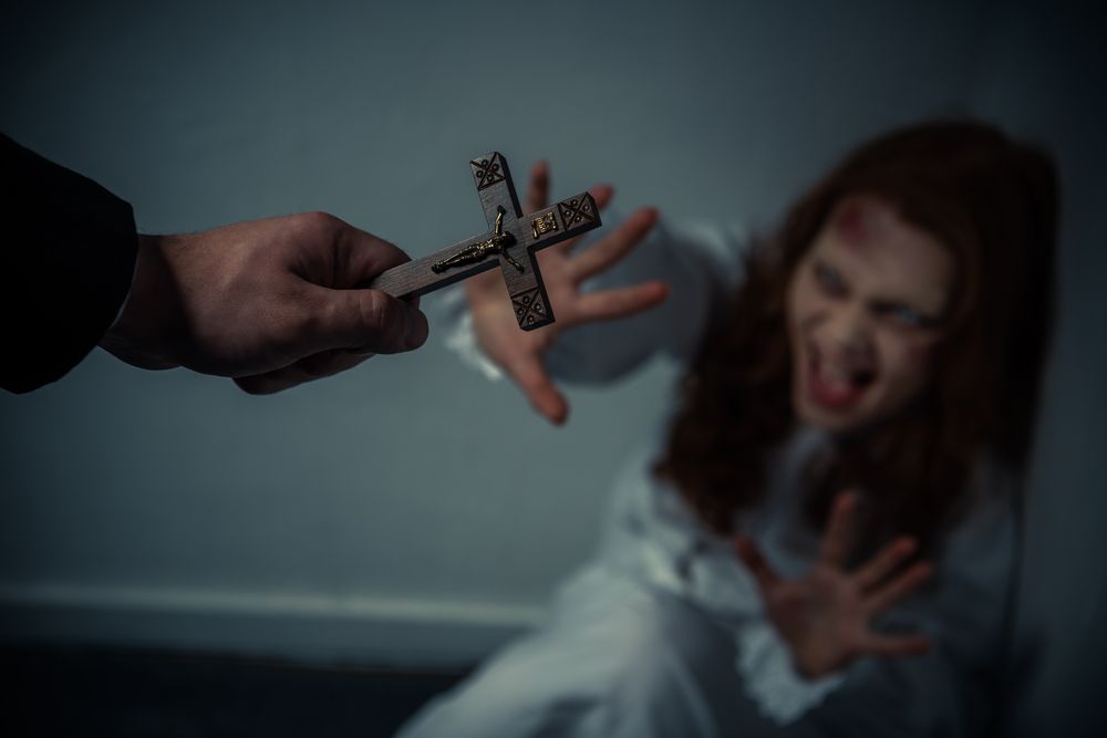 A priest holding a small cross during an exorcism