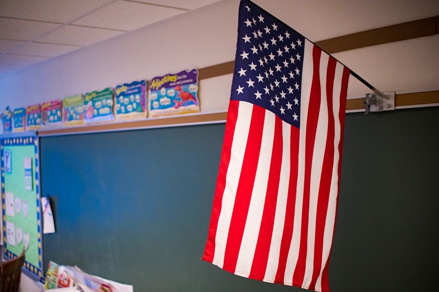 American flag hanging above chalk board in classroom