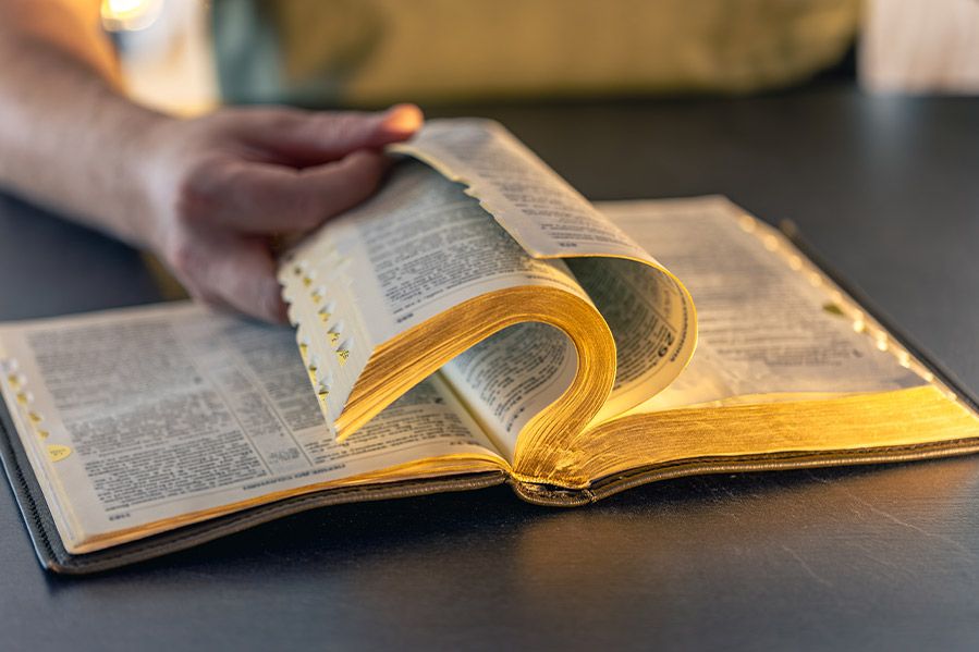man flipping through open bible on table