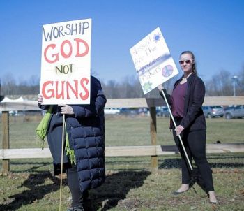 People gather to protest a church gun ceremony