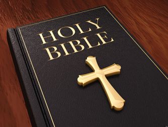 A bible sitting on the desk of a teacher.