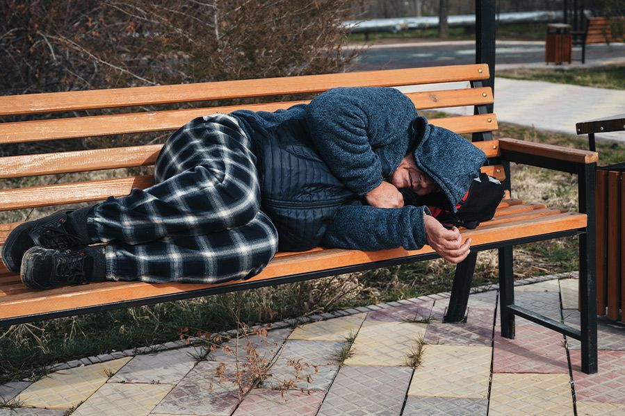 homeless man laying on bench