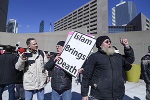 A man at a protest holds a sign that reads "Islam brings death"