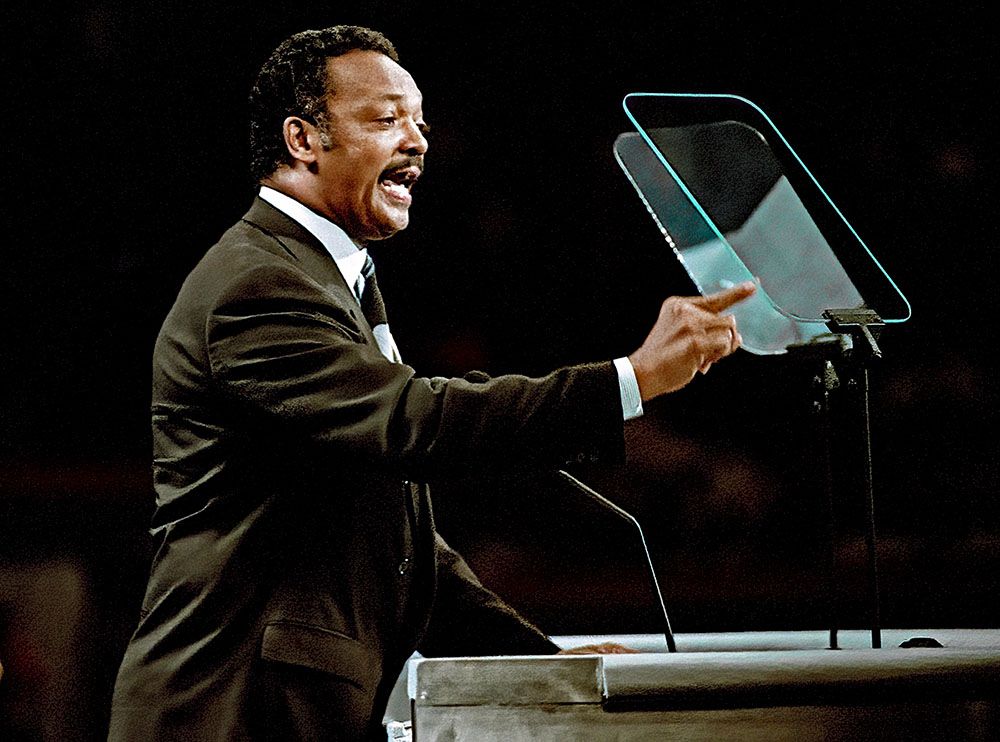 Jesse Jackson delivers a speech in a dark room.