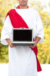 Man in religious garb holding a laptop