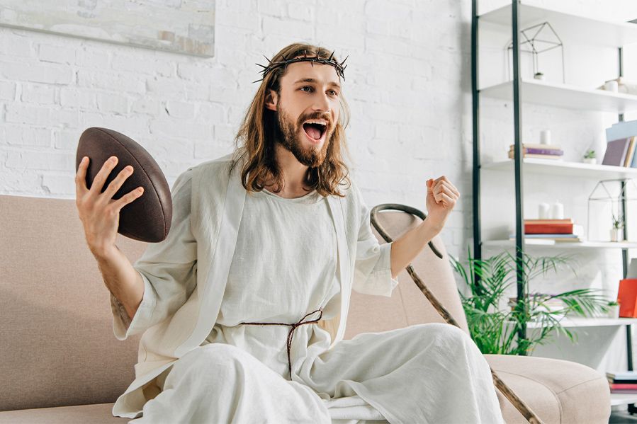 Jesus Christ sitting on couch, cheering and holding football