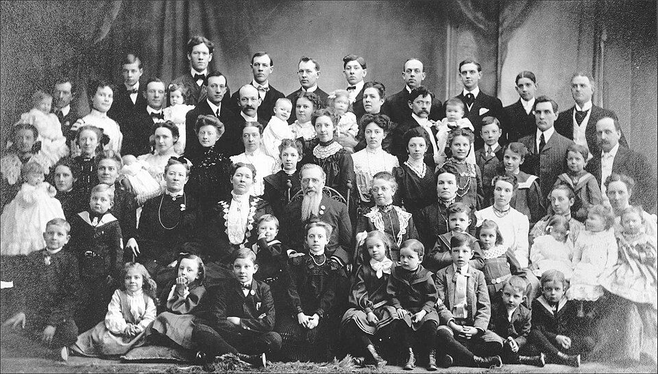 Joseph F. Smith and his five wives seated among several rows of their children in a formal outdoor family portrait.
