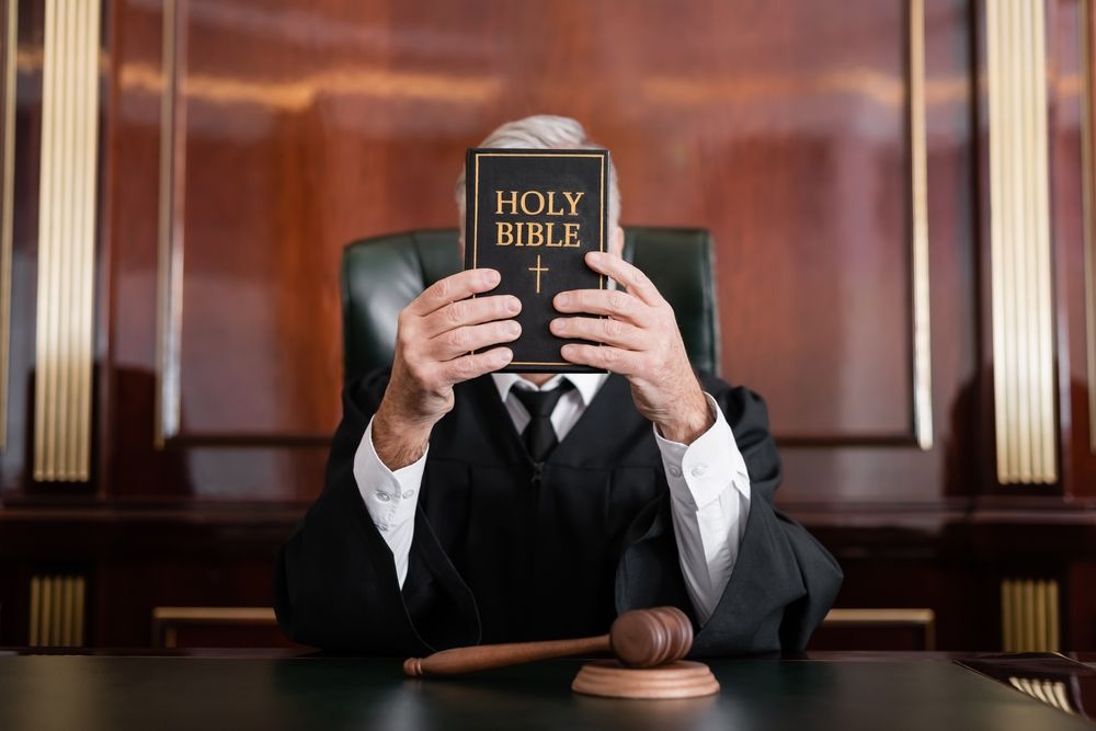 A judge hiding his face behind a bible