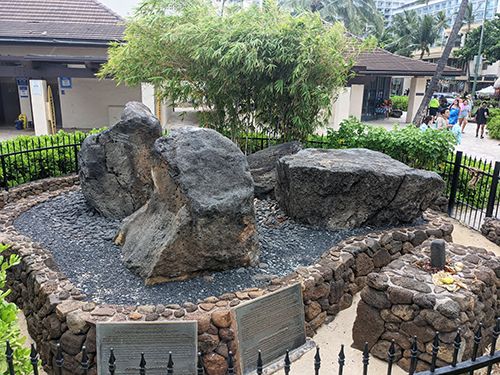 The four stones of the mahu surrounding by buildings and plaques in Hawaii.