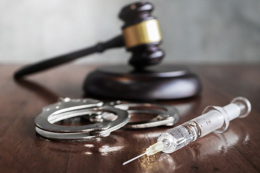 syringe and handcuffs on legal desk