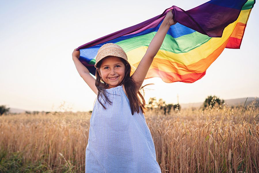 little girl in field holding pride flag