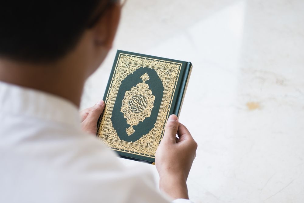 over the shoulder view of man holding quran