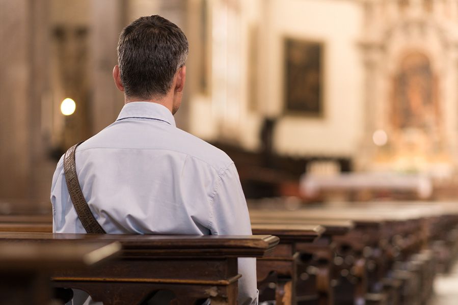 man sitting alone in church pews