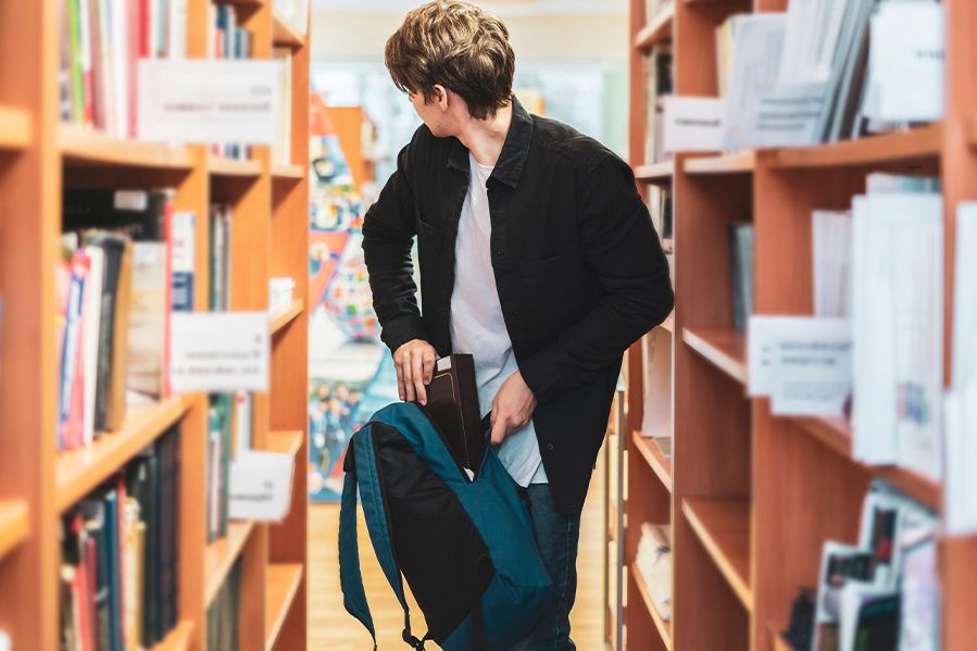 man stealing book at library