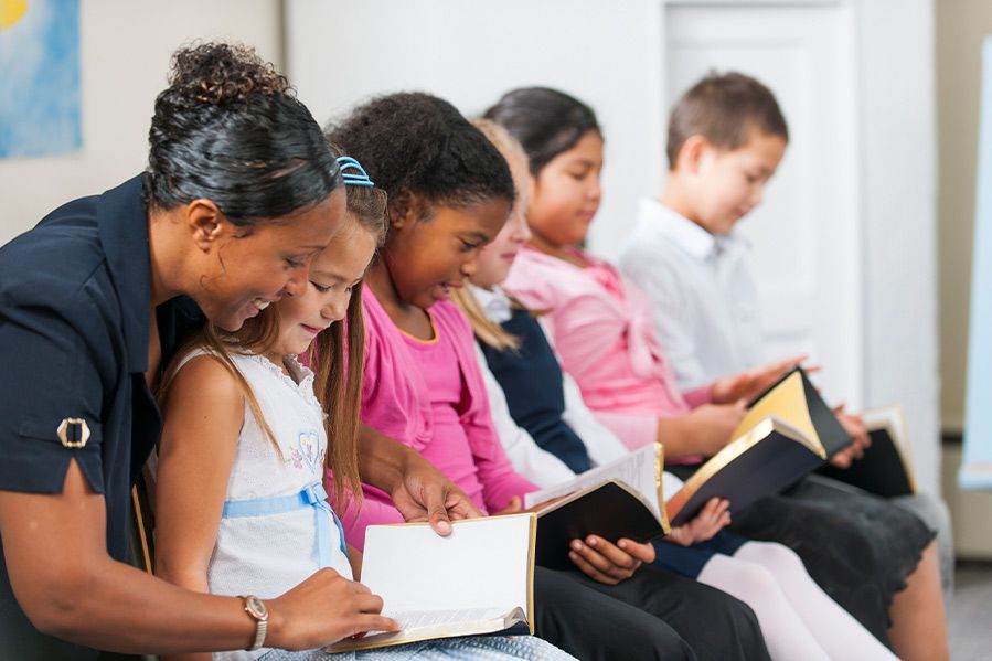teacher reading bible with students in classroom