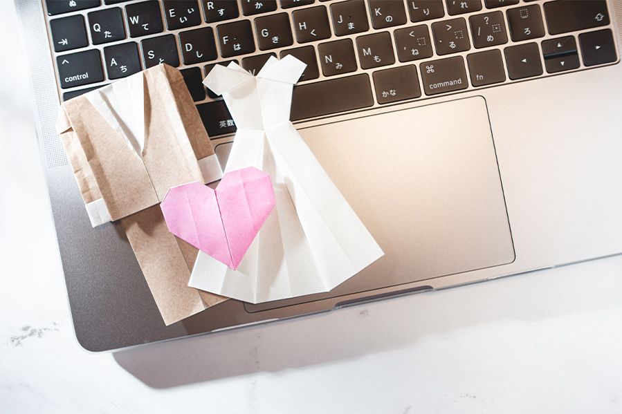 paper wedding dress and suit resting on computer