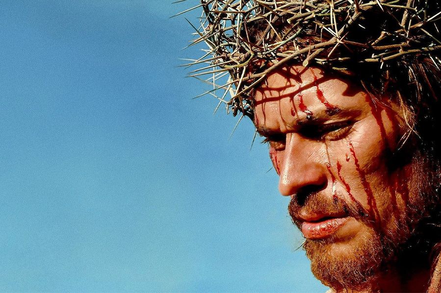 A close-up of an actor portraying Jesus bleeding whilst wearing a crown of thorns.