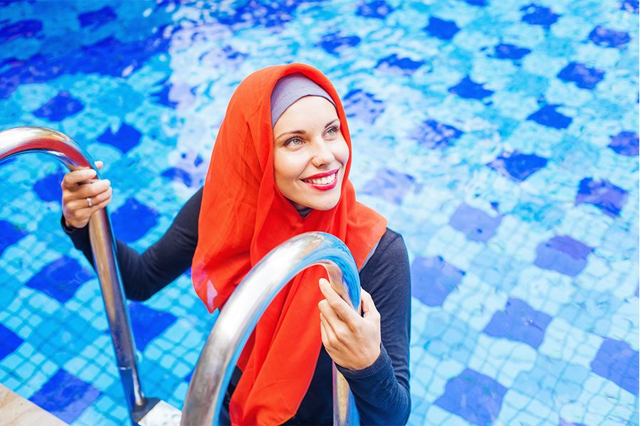 muslim woman wearing a burkini in a public swimming pool