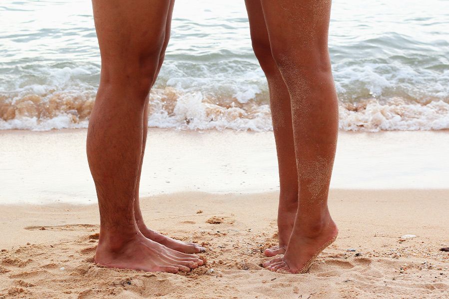 nudist couple exchanging kiss on beach